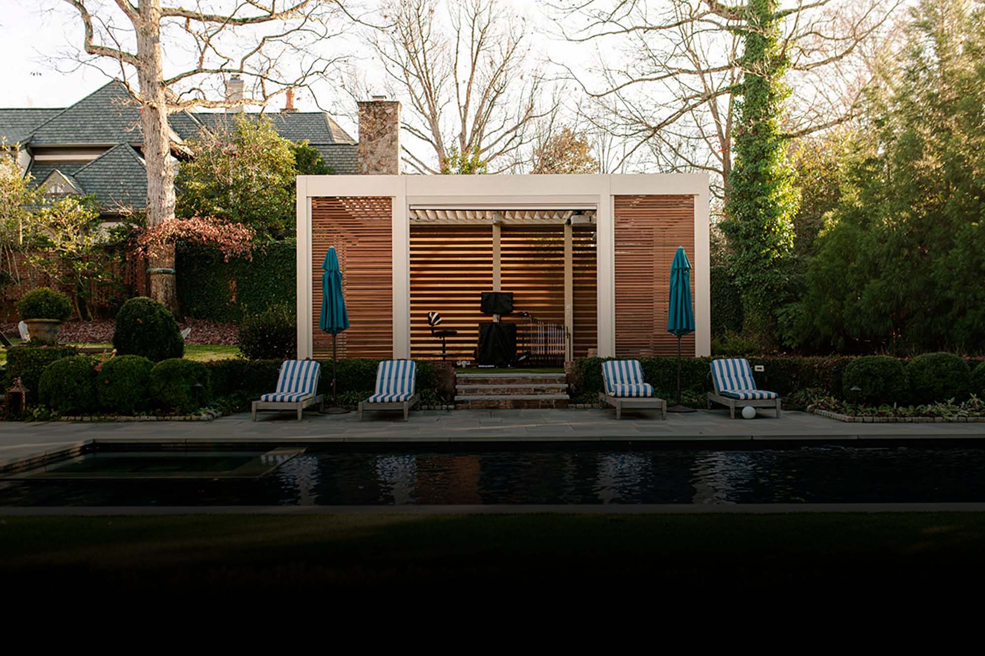 Freestanding smart louvered pergola in Charlotte, NC with automated screen, privacy walls, fans, heaters and golf simulator.